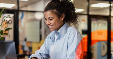 imagem de uma mulher sorrindo em frente de um notebook